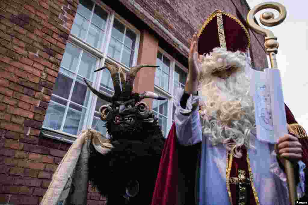 Persoane îmbrăcate în Sfântul Nicolae și Krampus, spiritul malefic cu coarne specific Germaniei și Austriei, vizitează un târg de Crăciun din Berlin și oferă cadouri copiilor, pe 6 decembrie 2025.