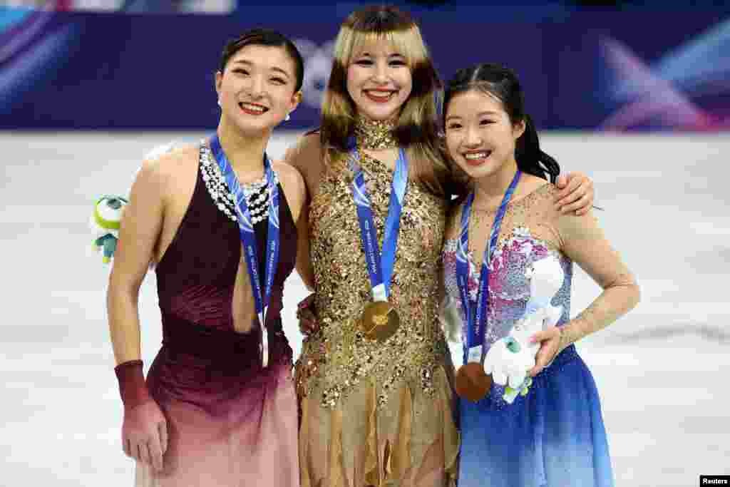 Золотая медалистка Алиса Лю из США празднует на подиуме после победы в одиночном катании среди женщин вместе с серебряной медалисткой Каори Сакамото из Японии и бронзовой медалисткой Ами Накаи из Японии. REUTERS/Claudia Greco