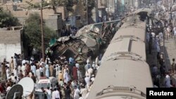 Spectators watch as rescue workers search a train that crashed in Karachi on November 3.