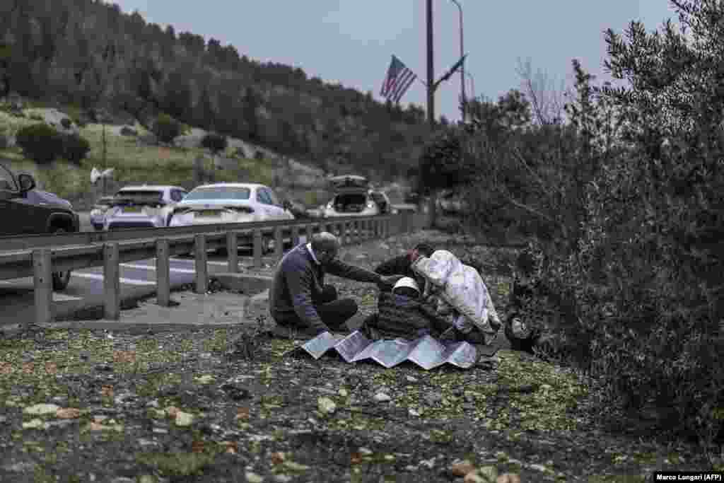 A man holds a child's helmet in place on a road in Latrun, central Israel, on April 1 during an Iranian missile attack.