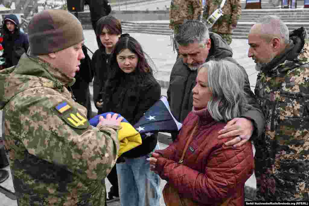 Леслі та Джон Гертвеки, батьки 21-річного Ітана Гертвека, отримують прапор України, яким була вкрита домовина з тілом їхнього сина під час церемонії прощання на майдані Незалежності в Києві, лютий 2025 року