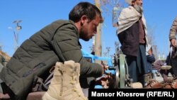 اسماعیل رضایی در کنار جاده خاکی شهر فیروزکوه مرکز ولایت غور کفاشی می‌کند