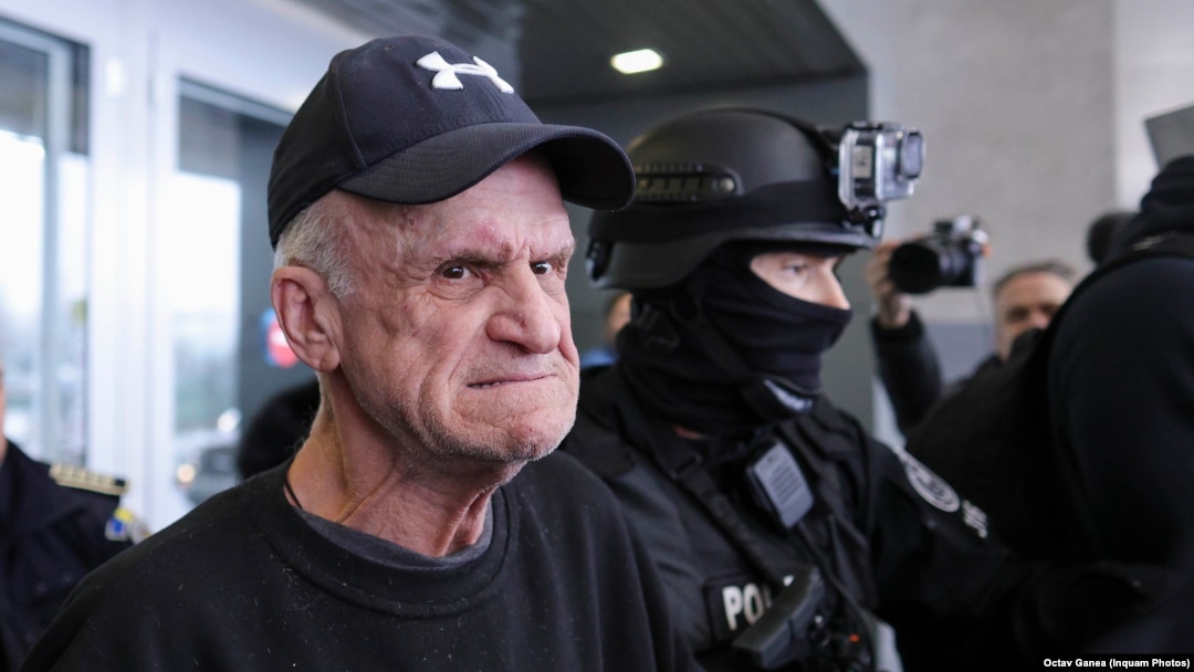 Nati Meir este ecortat de forțele de ordine la aducerea acestuia în România, din Grecia, pe Aeroportul Otopeni, 27 decembrie 2024.