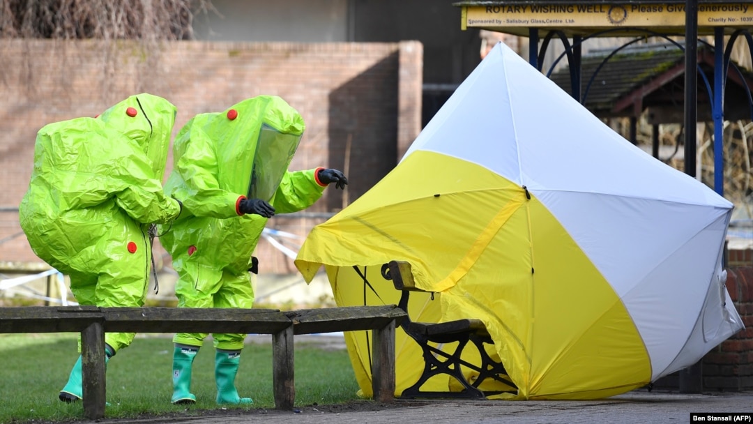 Members of the emergency services in green biohazard suits afix the tent over the bench on March 8 where a man and a woman were found on March 4 in critical condition in Salisbury.