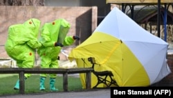 British emergency service workers in green biohazard suits place a the tent over the bench where Sergei Skripal and his daughter, Yulia, were found in critical condition on March 4.