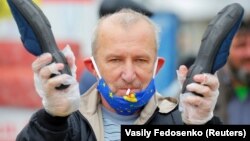 Bielorusia: manifestant cu mască anti-COVID-19 izbește o pereche de papuci, semn al revoltei împotriva lui Aleksandr Lukașenka.