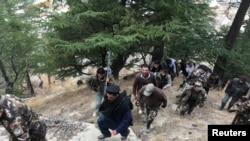 FILE: Afghan security forces and local elders walk towards a check post in Parun, capital of Nuristan province.