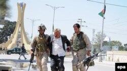 Afghan policemen forces help a man wounded in a militant attack in Mazar-e Sharif, capital of Balkh province on April 9.