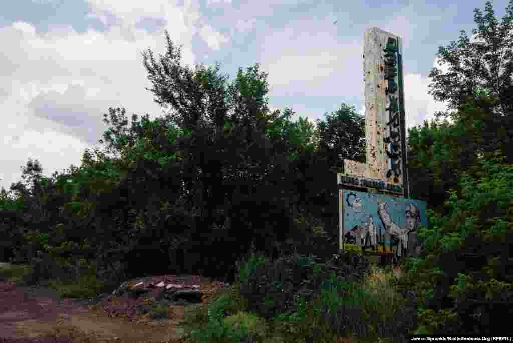 An old sign for Dzerzhynsk is scarred by bullet holes.