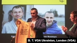 Oleg Sentsov ve Amnesty International Büyük Britaniya müdiri Kate Allen. Ekranda – Rusiyede mahkum etilgen Ukraina vatandaşları. Londra, 2019 senesi noyabrniñ 19-nda