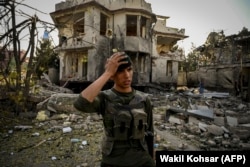 An Afghan soldier stands guard at the site of a car bomb explosion in Kabul on August 4.