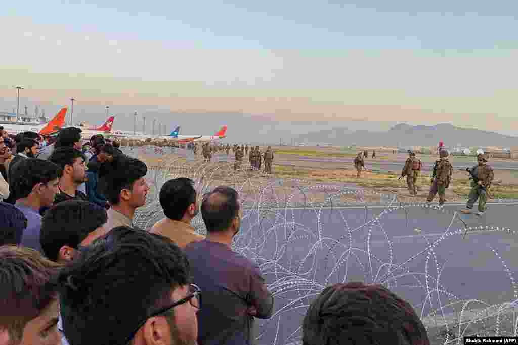 Afghan crowds gather at the airport as U.S. soldiers stand guard.&nbsp;