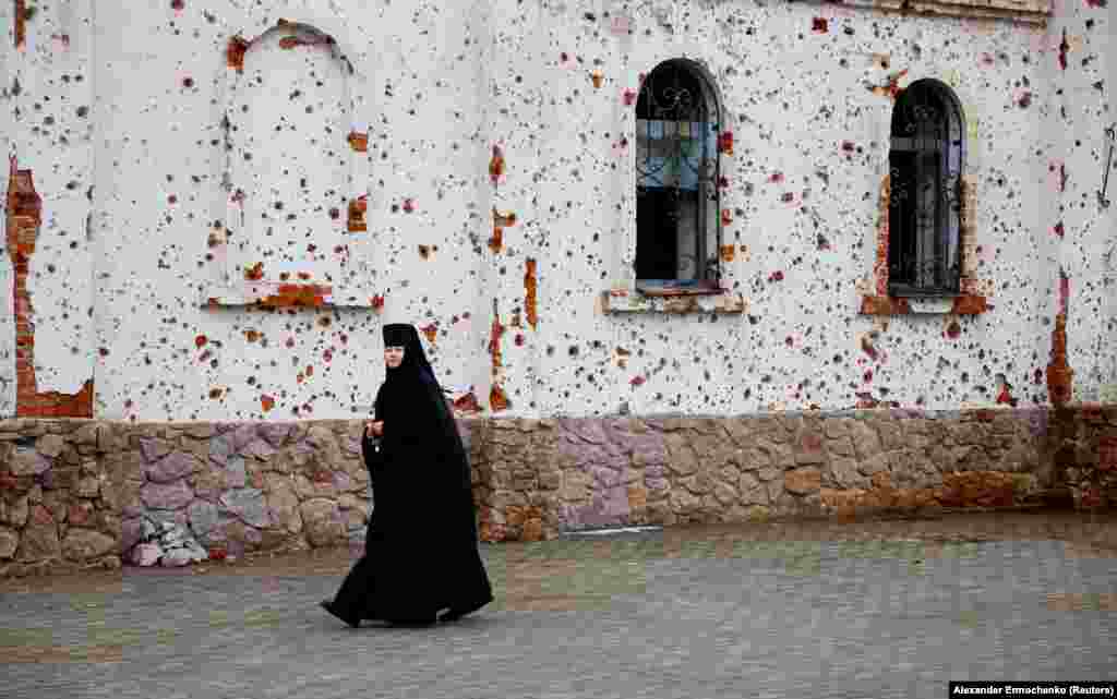 A nun walks outside a monastery that has been heavily damaged by artillery and gunfire in Ukraine&#39;s Russian-occupied Donetsk region.&nbsp;