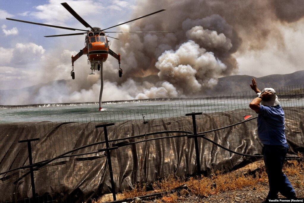 Një helikopter duke mbushur ujë nga një rezervuar, teksa një zjarr i egër digjte sipërfaqe pranë fshatit Spathovuni, afër Korintit, në Greqi. (23 korrik)