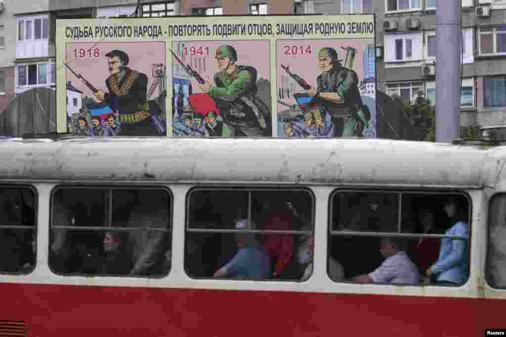 People ride a tram in the eastern city of Donetsk on July 8, &nbsp;in front of a sign&nbsp;saying, &quot;The fate of the Russian people is to repeat the exploits of their fathers while defending their native land.&quot; (Reuters/Maksim Zmeyev)