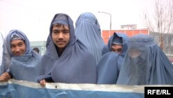 Афганские активисты в парандже проводят акцию на улице, пытаясь привлечь внимание общественности к проблеме нарушения прав женщин. Кабул, 5 марта 2015 года.