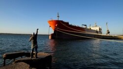 Un bărbat pescuiește lângă un vas sub pavilion cubanez la terminalul din Matanzas, unde ar urma să fie descărcat și petrolierul rusesc.