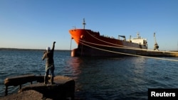 Un bărbat pescuiește lângă un vas sub pavilion cubanez la terminalul din Matanzas, unde ar urma să fie descărcat și petrolierul rusesc.