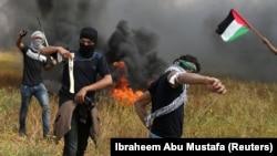 Palestinieni provocînd trupele israeliene la frontiera cu Gaza