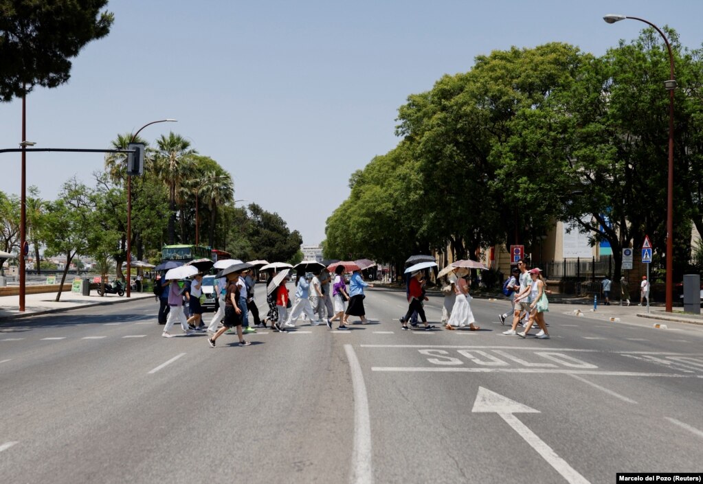 Turistë duke u mbrojtur me ombrella dielli në Sevillë, më 29 qershor.
