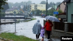 Ljudi stoje u blizini poplavljene ulice nakon jake kiše u Pisecni, Češka, 14. 9. 2024.