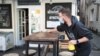 Egy csapos maszkban fertőtleníti az egyik asztalt egy ljubljanai kávézó teraszán 2020. május 4-én