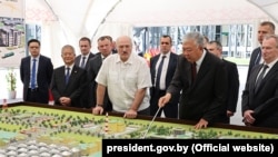 Belrusian President Alyaksandr Lukashenka (center) visits the Belarusian Biotechnological Corporation on August 10 with a man (holding the pointer) who looks like Kyrgyzstan's wanted former prime minister, Daniyar Usenov.