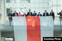 Дэпутаты Эўрапарлямэнту побач зь беларускі нацыянальным сьцягам