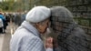 An elderly Russian woman, a granddaughter of a Stalin terror victim, touches her head to a name of her grandfather, written on the memorial wall at Butovo shooting range outside Moscow.