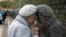 An elderly Russian woman, a granddaughter of a Stalin terror victim, touches her head to a name of her grandfather, written on the memorial wall at Butovo shooting range outside Moscow.