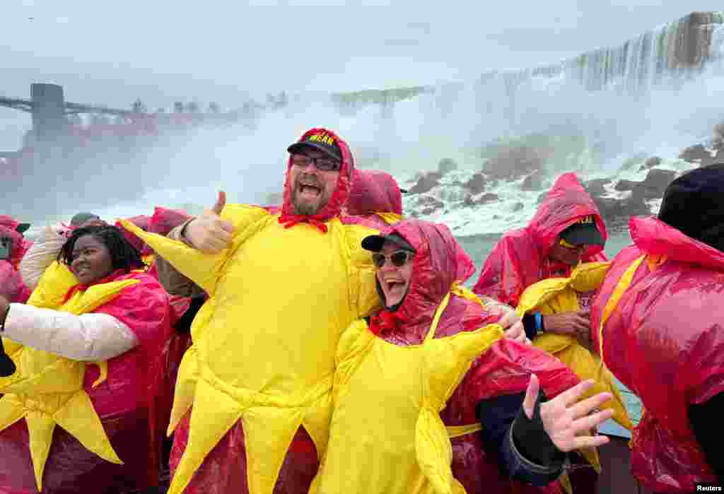 Niagara Falls, Ontario, Canada - 309 oameni s-au îmbrăcat în soare, dar și cu pelerine de ploaie pentru a se proteja de apa Cascadei Niagara. Aceștia vor să doboare recordul mondial Guiness cu cel mai mare grup de oameni îmbrăcați în poza soarelui pe o barcă cu care vizitează obiectivele turistice ale zonei înainte de eclipsa totală de soare.