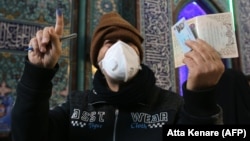 An Iranian man wearing a face mask, shows his ink-stained finger, meaning he just cast his vote in parliamentary elections at a polling station in Tehran on February 21. The election was held amids fears of a coronavirus outbreak in the Middle Eastern country. 