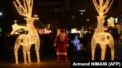 Një burrë i veshur si Babadimër para dekorimeve për festa në Prishtinë, më 21 dhjetor 2024.