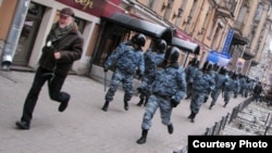 Yuly Rybakov, clutching a white carnation, is chased down by Russian Interior Ministry police in St. Petersburg in November 2007. (Photograph by Alexandr Kogtev)
