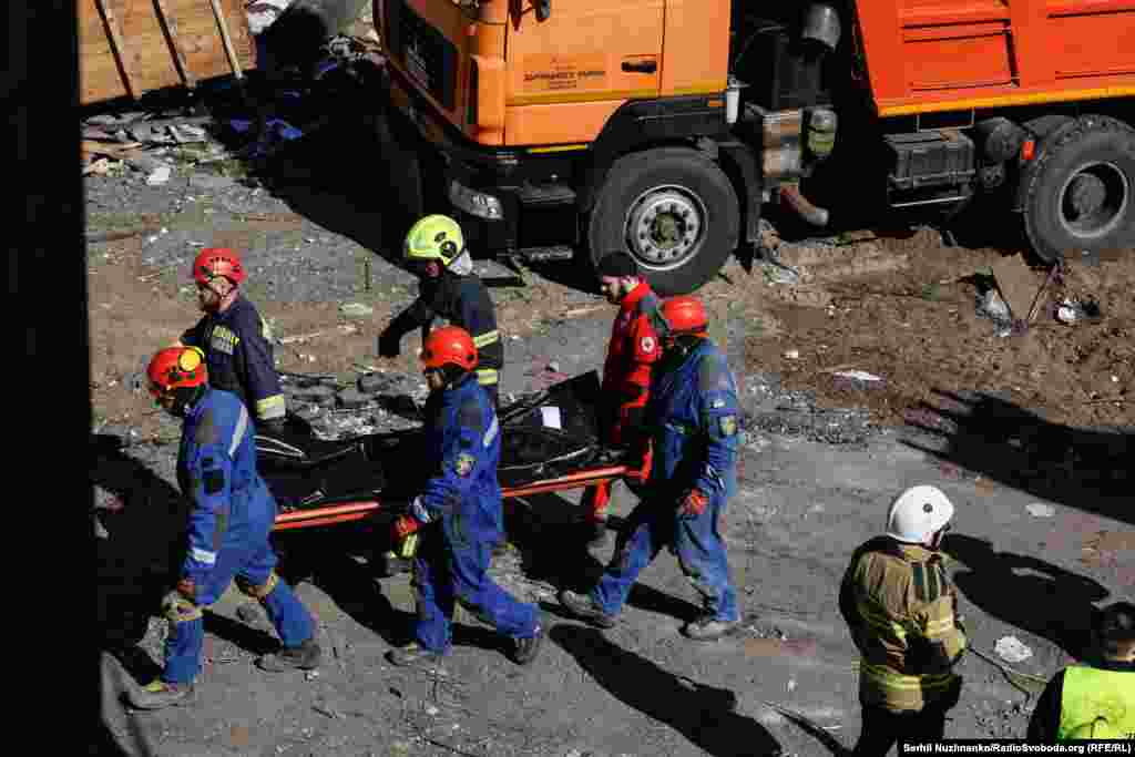 Рятувальники несуть тіло людини, яке деблокували з-під завалів 