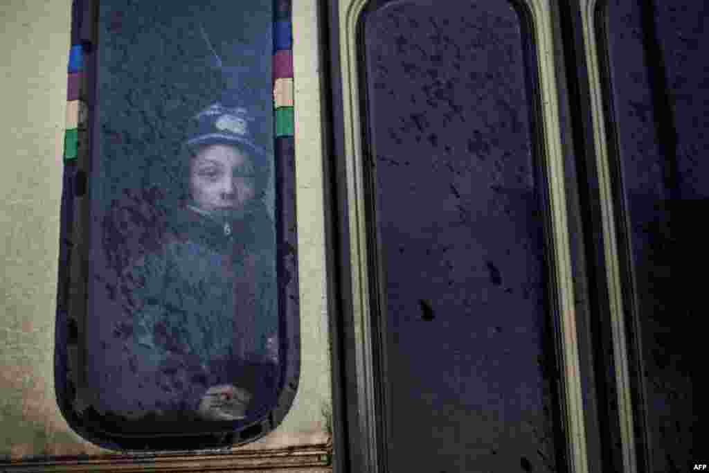 A young boy looks out the window of a bus before fleeing fighting in the Ukrainian city of Debaltseve in the eastern Donetsk region. Civilians fleeing the besieged city came under withering artillery fire from pro-Russian separatists on February 1, with Ukrainian security forces vowing to fight to the end to defend the key transport hub. (AFP/Manu Brabo)