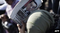 A woman shields herself from the sun with a newspaper bearing a portrait of deposed President Hosni Mubarak during celebrations on Cairo's Tahrir Square on February 18.