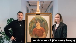 Кіраўнік ініцыятывы Maldzis Павел Мацукевіч і мэнэджэрка Тацяна Капітонава з карцінай Міхаіла Кікоіна, набытай на аўкцыёне ў Ізраілі. 27 кастрычніка 2026 года, Варшава, Польшча