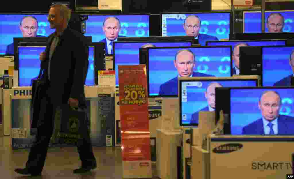 Russia -- A customer walks past the TV screens in a shop during the broadcast of President Vladimir Putin's televised question and answer session with the nation, Moscow, 25Apr2013