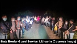 Grup de migranți deținuți la granița dintre Lituania și Belarus.