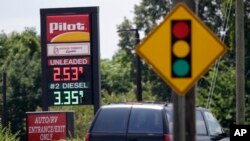 In this photo taken Thursday, June 14, 2018 an automobile drives past signage displaying gas prices at a Pilot gas station near Graham, N.C. 