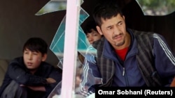 Afghan men look out through a broken window at the site of a suicide attack in Kabul on April 22.