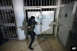 A man breaks the lock of a cell in the infamous Saydnaya military prison, just north of Damascus, on December 9.