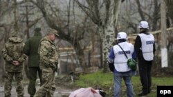 Донецк облысының Широкино елді мекенінде ұрыста қаза тапқан "Азов" батальонының ерікті сарбазы маңында тұрған ЕҚЫҰ бақылаушылары мен украин әскері. Донецк облысы, 15 сәуір 2015 жыл.