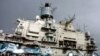 Naval personnel stand in front of the Russian aircraft carrier Kuznetsov in the Syrian city of Tartus in the Mediterranean sea, January 8, 2012