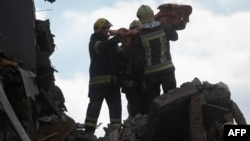 Echipele de salvare duc un copil găsit sub dărâmături în urma unui atac rusesc la Priluki, Ucraina, pe 7 octombrie. 