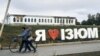 UKRAINE – Residents walk their bikes past a city sign reading ''I Love Izium'' in Izium, Kharkiv region, September 13, 2022