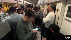 Fotografi arkivi: Udhëtarët shikojnë telefonat e tyre celularë teksa udhëtojnë me metro në Teheran.