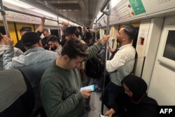 Commuters looks at their mobile phones while traveling on the subway in Tehran.