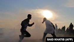 Palestinians run for cover from tear gas during clashes near the border between Israel and Khan Yunis in the southern Gaza Strip on November 9, 2018